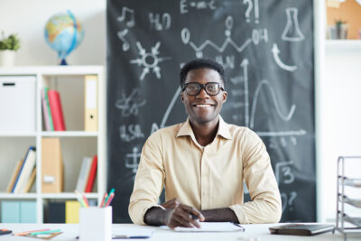 stock photo of teacher at school, blackboard in the background